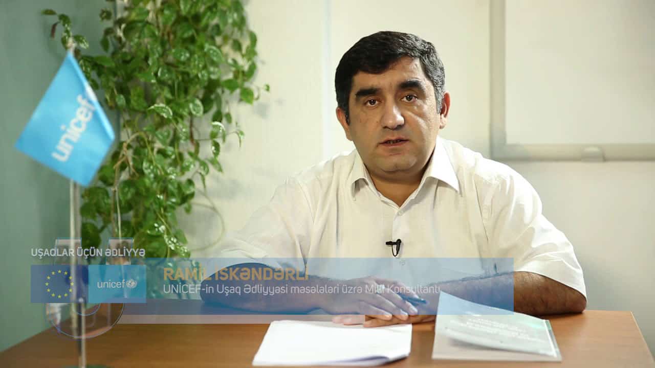 Man sitting at desk with a UNICEF flag