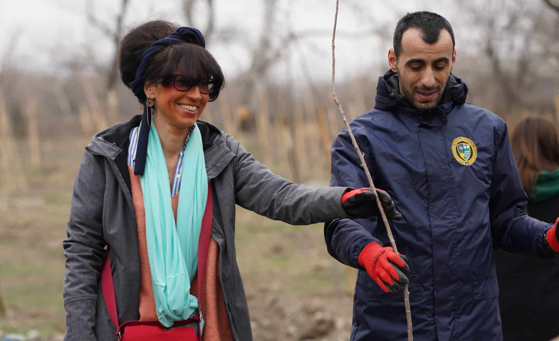 A woman and man planting seedlings in a forest