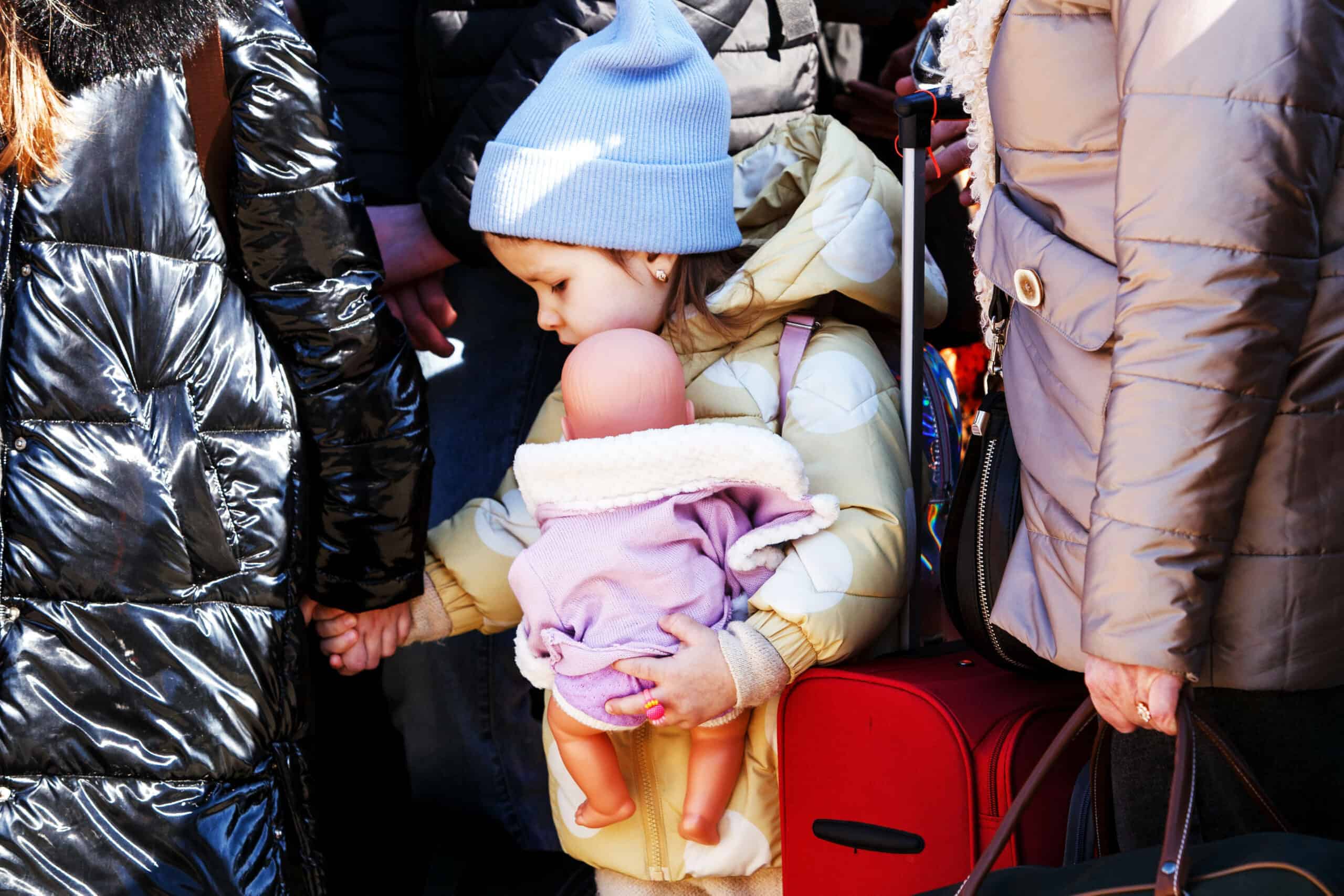 Little girl in a crowd holding woman's hand