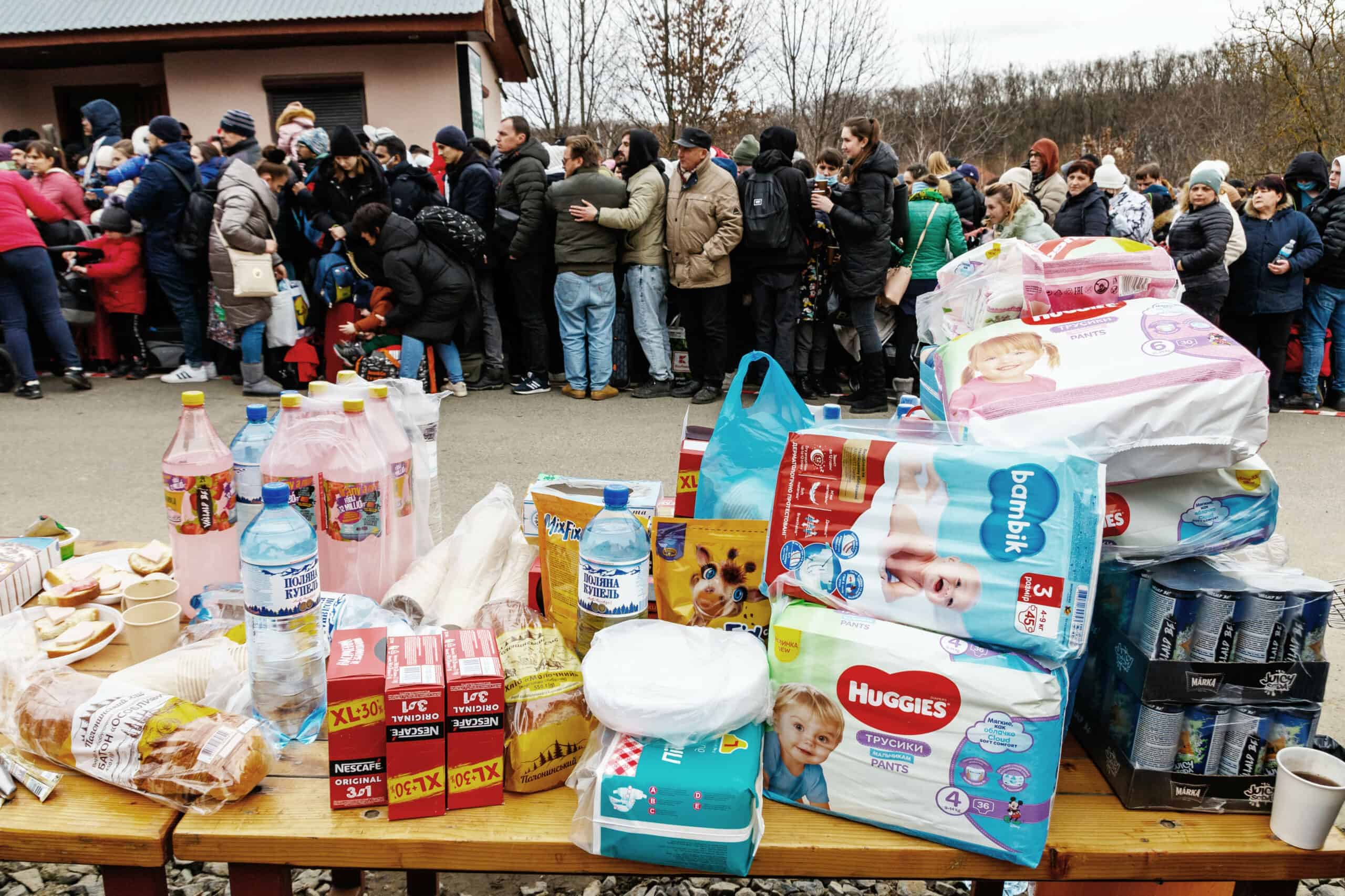 Table of supplies next to line of displaced people