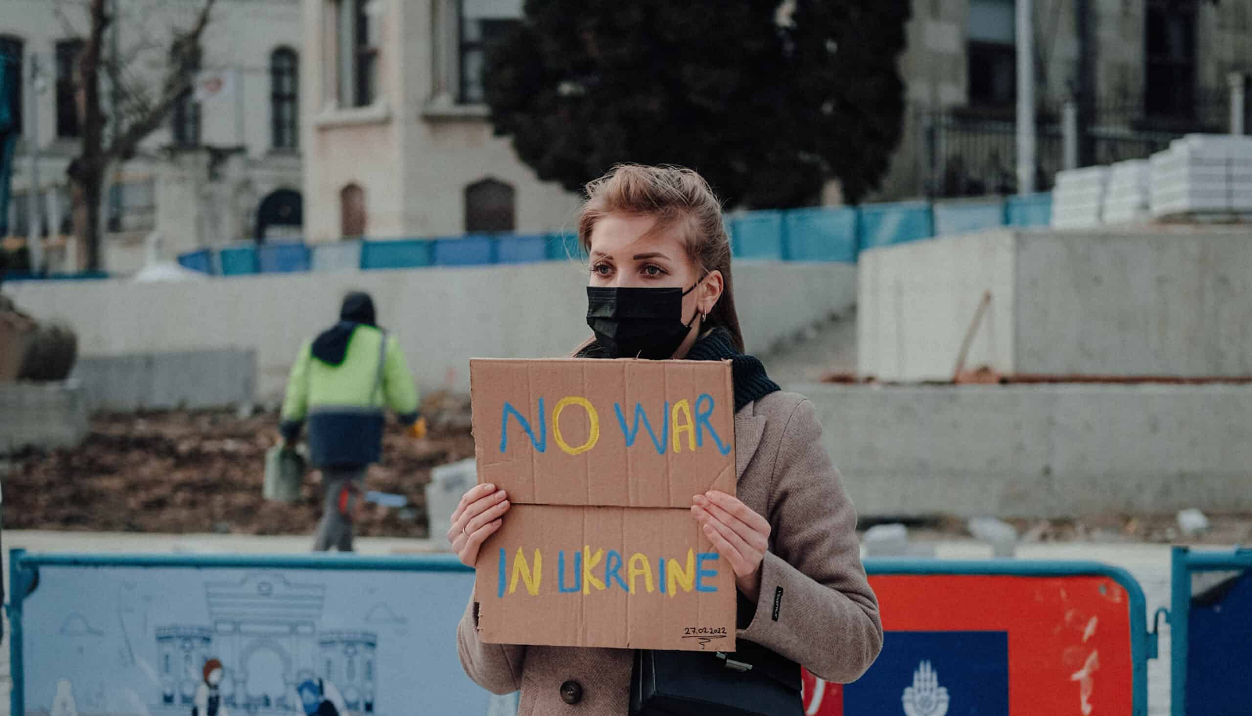 Female war protestor stands alone with banner