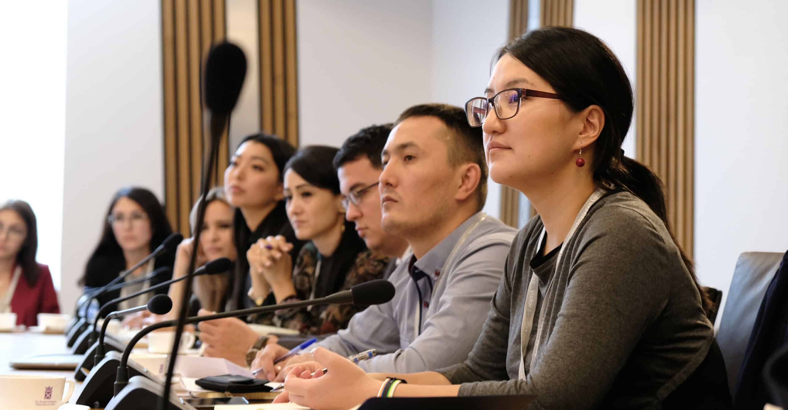 A row of people at a desk with microphones