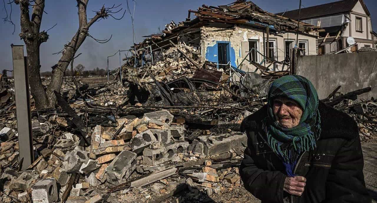 Old woman in front of bombed house