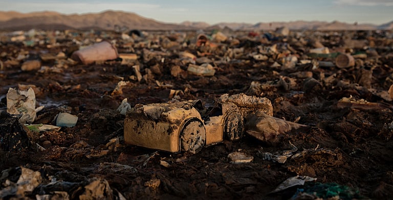 plastic debris littering the muddy shores of a lake