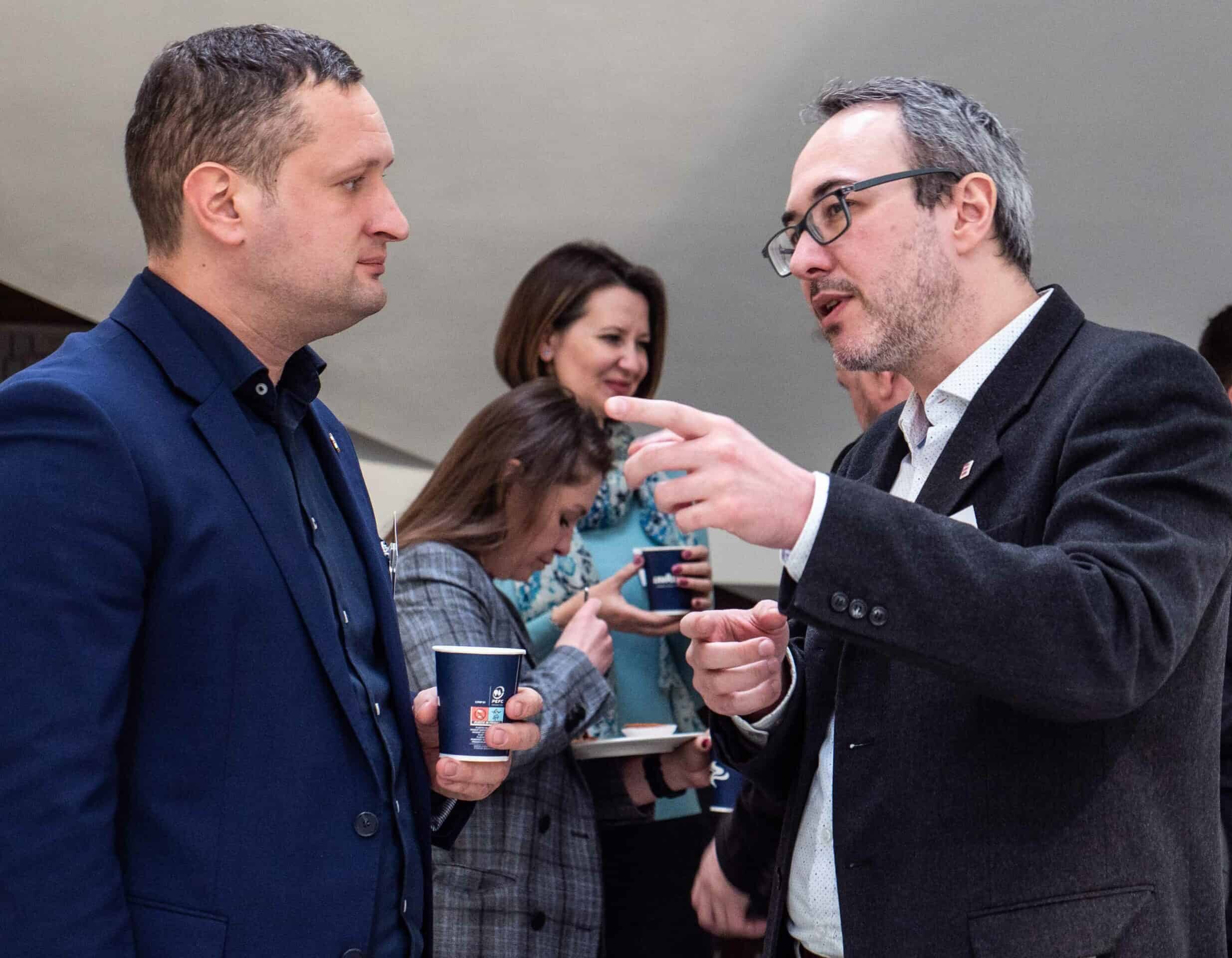 Two men talking with one man pointing away, two women in background