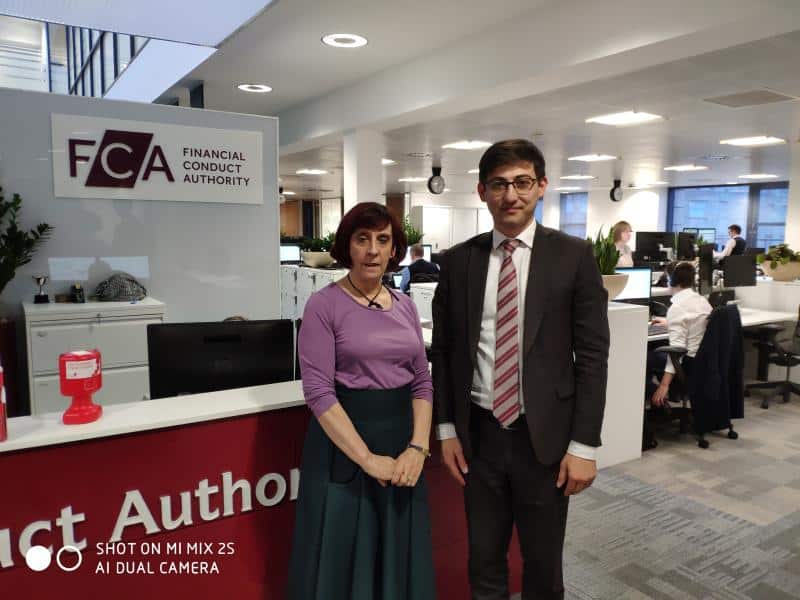 A man and a woman standing next to each other in Financial Conduct Authority office.